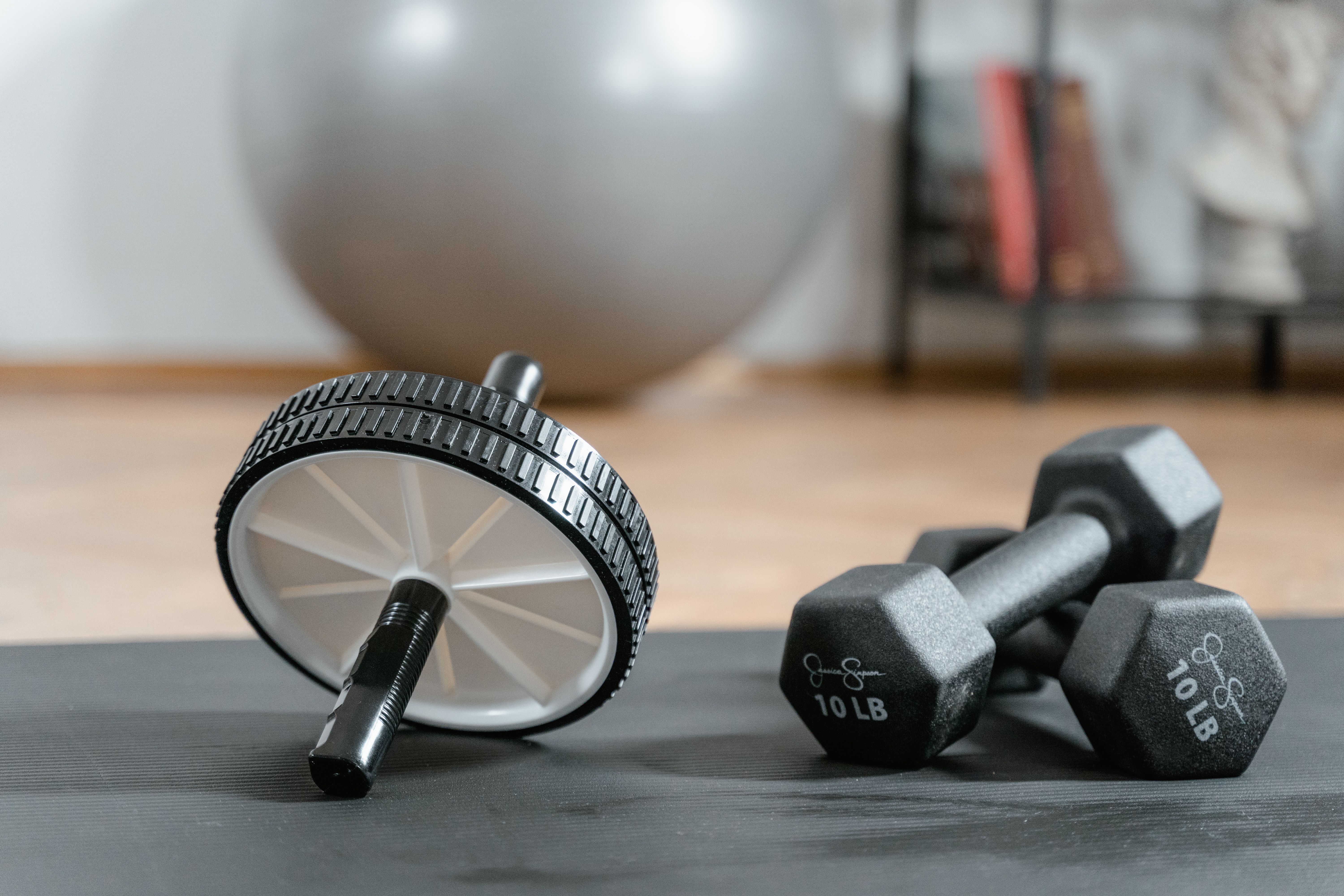 Close-up of an ab wheel and dumbbells on a mat in a home gym