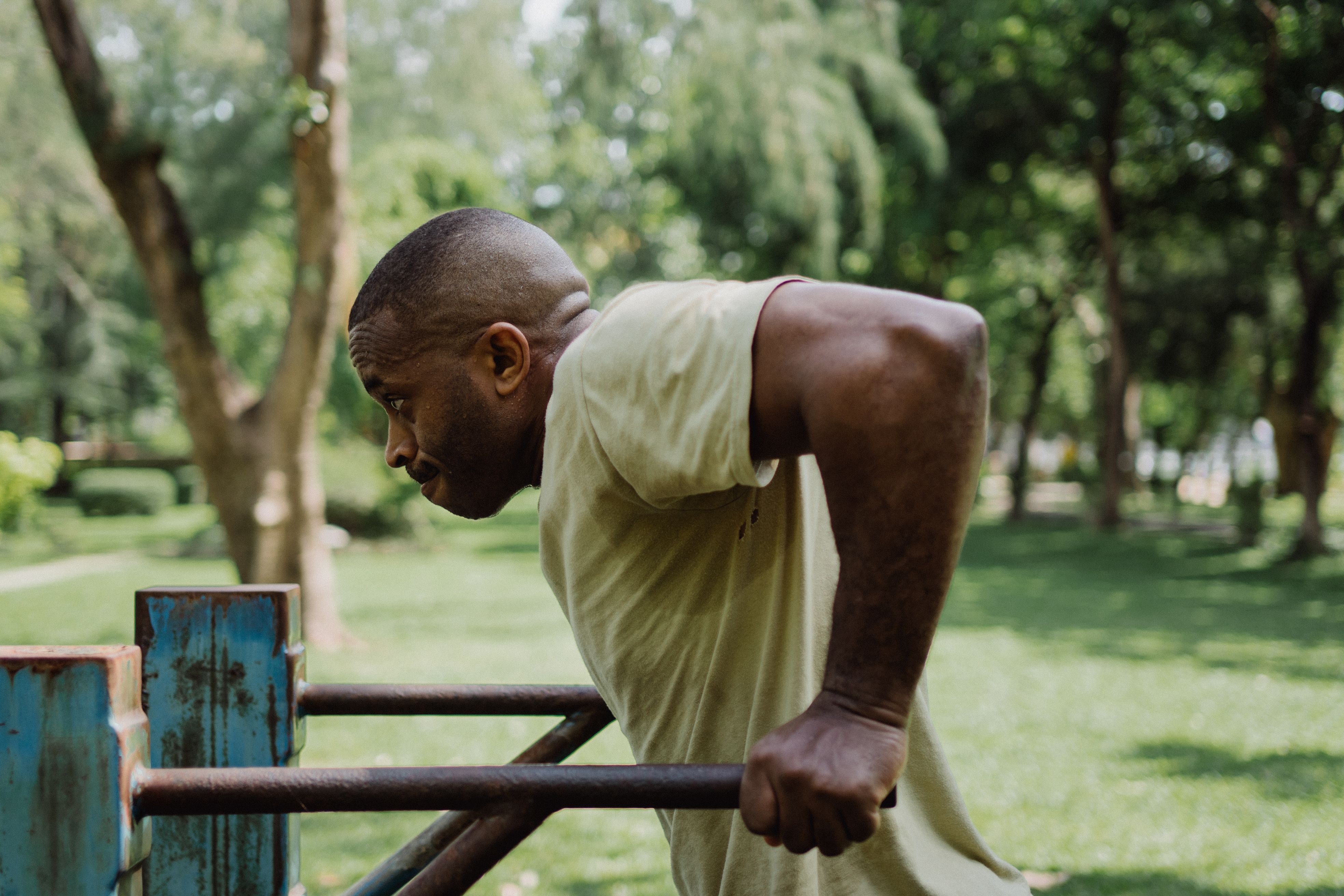 A man doing dips on parallel bars in a lush outdoor park